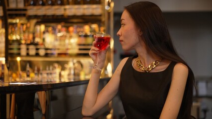 Sitting beautiful drinking alone in Cosmopolitan red cocktail waiting friends or couple at bokeh...