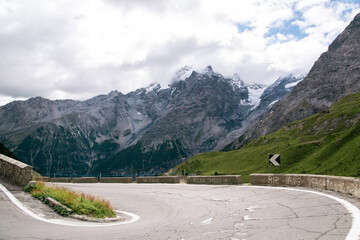 One of the iconic hairpins of the Stelvio pass, with rocky mountain peaks and glaciers in the...