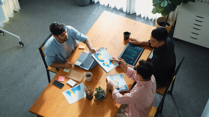 Executive manager explain financial graph to colleague at meeting room. Top aerial view of diverse marketing team sharing idea and planning strategy while sitting at table with tablet. Convocation.