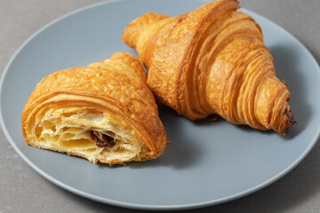 Freshly baked croissants served on a blue plate with chocolate filling for breakfast or snack time
