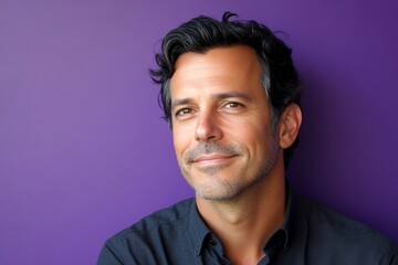 Obraz premium A strong and confident man with an engaging smile. Purple solid background. Trendy men's textured crop haircut - midlife white man with black hair. Creative of style for aging men.