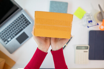 businesswoman in red shirt standing holding parcel box ready to deliver to customer who ordered...