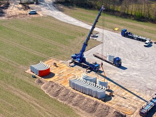 Tower segments are lowered by a crane onto a construction site for a wind turbine, construction site, wind turbine, energy transition, tower, prefabricated parts, hybrid tower, concrete parts