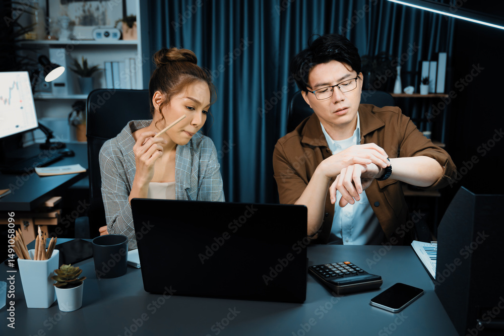 Poster sales managers waiting email sending back while looking watch with overtime for working report data 