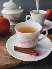 white porcelain cup with apple and cinnamon tea and dark background