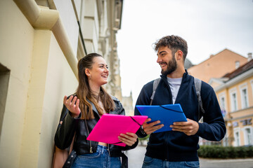 Two Students Walking and Studying Literature Together Outdoors