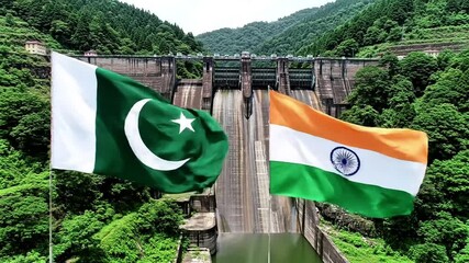 Pakistan and india flags waving in front of a dam surrounded by lush trees