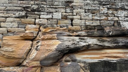 Textured contrast between man-made brick wall and natural eroded sandstone rock. Ideal for backgrounds, architecture, and geology themes.