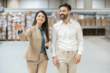 Woman pointing while discussing operations with coworker in warehouse