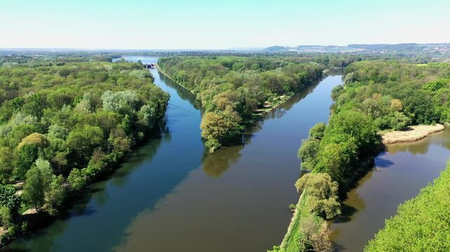 Die Lechm&uuml;ndung in die Donau zeigt eine friedliche Flusslandschaft mit &uuml;ppiger Vegetation und klarem Wasser. Die Spiegelung der B&auml;ume im Wasser und der blaue Himmel schaffen eine idyllische Atmosph&auml;re