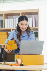 Asian woman starts a small SME business using her home as Home Office and checks inventory to...
