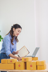 Asian woman starts a small SME business using her home as Home Office and checks inventory to ensure that there are enough items to deliver to customers according to orders. Small SME Business Startup