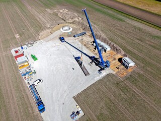 Tower segments are lowered by a crane onto a construction site for a wind turbine, construction site, wind turbine, energy transition, tower, prefabricated parts, hybrid tower, concrete parts