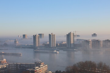 A misty landscape photo with the Nieuwe Maas River in Rotterdam, the Netherlands, in the background.