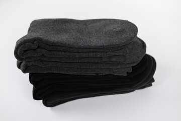 Stacked pairs of black and dark gray socks arranged neatly on a plain background