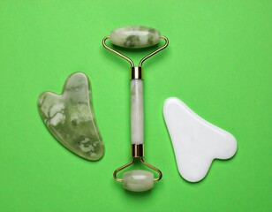 Green jade roller & gua sha tools for skincare on a green background