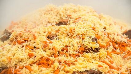 Tasty pilaf in a cauldron on fire in the open air at street food festival