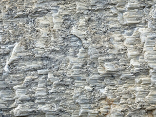 Rough textured light gray stone surface with natural layered patterns