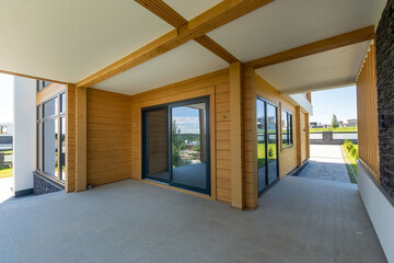 A spacious terrace near a luxurious mansion made of natural wooden beams, on a sunny .summer day.