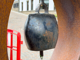 Rustic metallic cowbell hanging in urban street scene