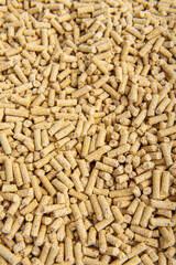 Beige granules. Vertical. Filler for cat litter box, fuel pellets or food for birds or goats