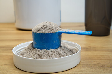 Whey protein powder in a measuring scoop close up