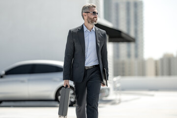 Successful businessman walk with with briefcase outdoors. Business man hold briefcase outside....