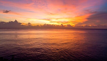 Ocean sunset fiery colors and calm water under a cloudy sky