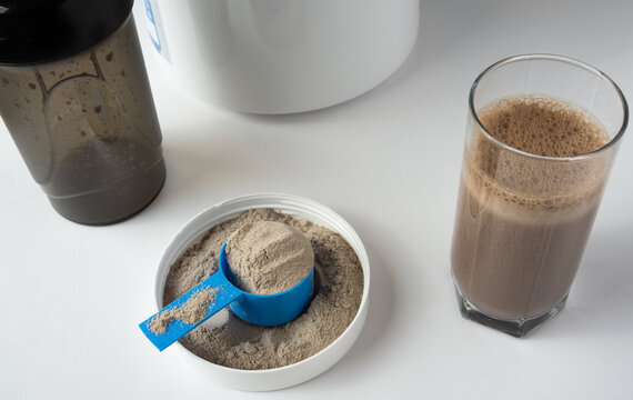 Protein shake in a glass and whey protein powder in a measuring scoop