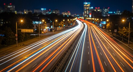 Obraz premium Cityscape at night with blurred car light trails on highway creating dynamic motion effect