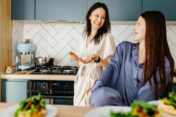 Teen girl and mom in robes checking phone at breakfast table