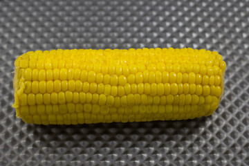 A fresh ear of corn featuring plump, bright yellow kernels, showcasing its natural sweetness and appeal, ideal for steaming or grilling as a delightful seasonal treat.