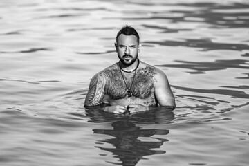 Shirtless muscular man swimming in a lake. Handsome athlete enjoying water in nature. Fit male...