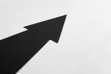 An arrow shadow on a light background, pointing upwards. Space for text.