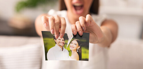 Divorce Concept. Unrecognizable Furious Girl Tearing Apart Photo Of Happy Couple Indoor. Selective...