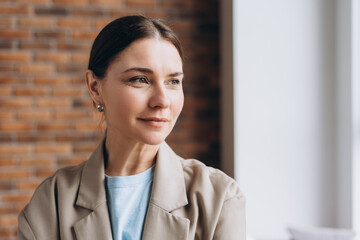 Businesswoman looking away and thinking near brick wall