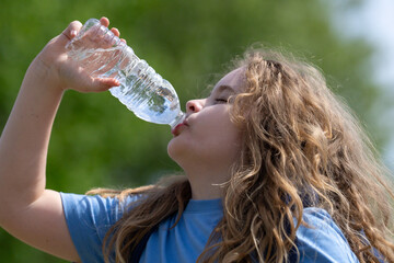 Thirsty child drinking water from bottle. Kid refreshing with drink. Thirsty child drink water from...