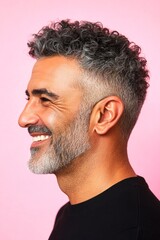 Obraz premium Modish men's low fade haircut - midlife middle eastern man with curly hair. A man with timeless elegance and a natural smile. Creative of style for aging men. Pink solid background.