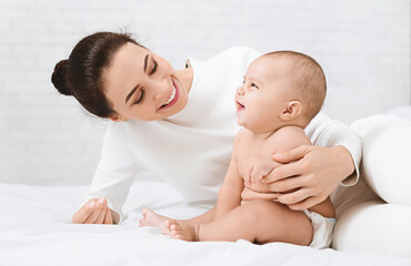 Happy childhood, Adorable baby laughing with mother, sitting on bed together