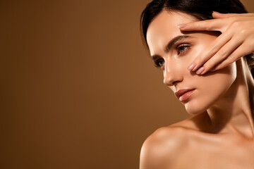 Portrait of a young brunette woman with flawless skin on a beige background