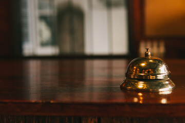 Vintage Brass Reception Bell on Wooden Counter in Elegant Hotel Lobby Setting with Soft Focus...
