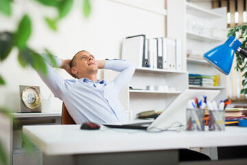 Naklejka premium Satisfied businessman leaned back in his chair after work done