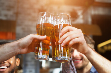 Cheers For Us. Men Drinking Draft Beer And Clinking Glasses At Pub, Closeup