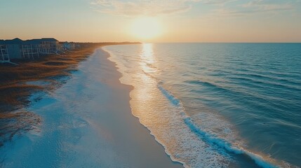Obraz premium Coastal sunrise over a pristine beach with homes on the horizon.