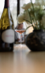 Bottle of rose champagne and wine glass is on table in the restaurant, flowers, wine cabinet,...