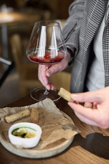 Champagne tasting in restaurant, A man holds in his hand a beautiful elegant glass with rose sparkling wine, He eats delicious snacks and drinks pink wine