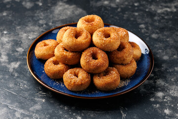 Mini cinnamon sugar donuts on blue plate