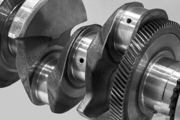 Close-up of a car crankshaft with visible gears. The shaft is made of metal and has a shiny...