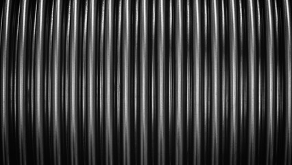 Obraz premium Close-up of black stainless steel corrugated pipe on black background. The image has a monochrome color scheme, which gives it a sleek and modern look, industrial texture concept background