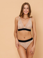Naklejka premium Girl model in underwear posing in studio on beige background.
